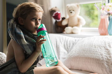 Little boy with chickenpox, drinking water from botle