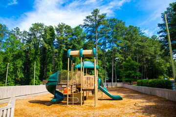 a brown and green jungle gym on a playground surrounded by lush green trees and plants at Dupree...