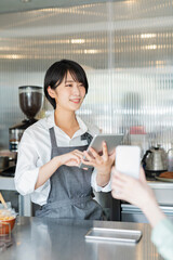 カフェ スタッフにスマートフォンを見せる女性