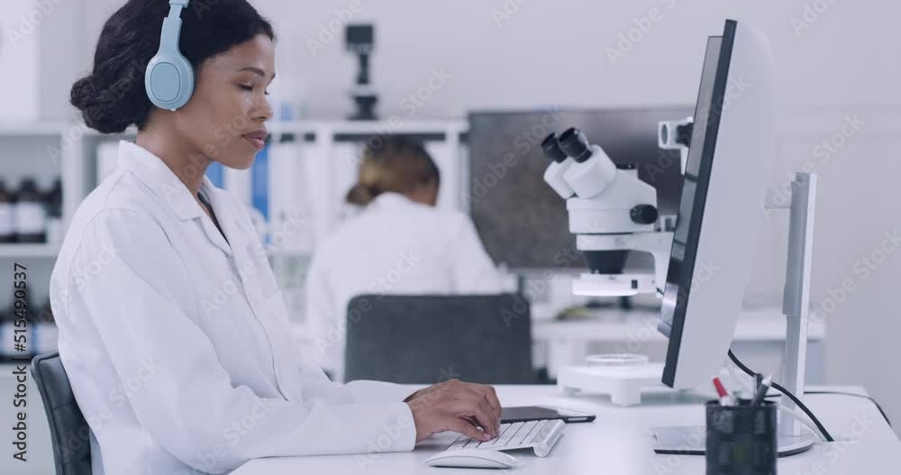 Poster Scientist using a computer and listening to music on wireless headphones while working in laboratory. Focused pathologist and biochemical engineer using technology in a medical research facility