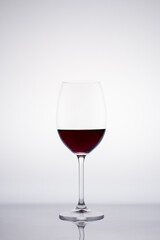 Glass of red wine in back light on white background
