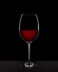 Glass of red wine in back light on black background