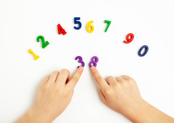 Children's hands move numbers on a white table. Learning colors and to count from zero to ten