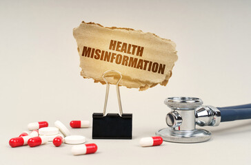 Near the stethoscope are pills and a clip with a cardboard sign - health misinformation