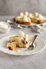 Homemade coconut cake with raspberries decorated with white chocolate and coconut candies. Light photo. Photo on a light gray background.