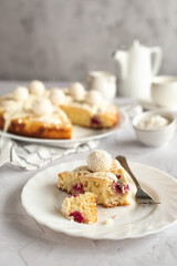 Homemade coconut cake with raspberries decorated with white chocolate and coconut candies. Light photo. Photo on a light gray background.