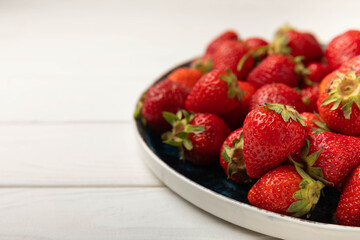 Fresh ripe strawberries in a plate on a white wooden background.Vegetarian organic berry.Healthy food.Vitamins.Copy space.Space for text