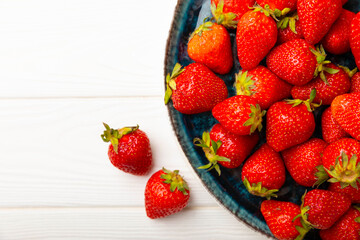 Fresh ripe strawberries in a plate on a white wooden background.Vegetarian organic berry.Healthy food.Vitamins.Copy space.Space for text