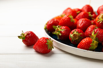 Fresh ripe strawberries in a plate on a white wooden background.Vegetarian organic berry.Healthy food.Vitamins.Copy space.Space for text