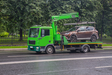 Fototapeta na wymiar Tow truck transports a car down the street