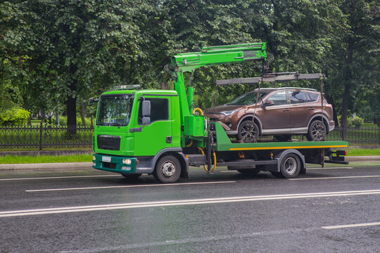 Tow truck transports a car down the street