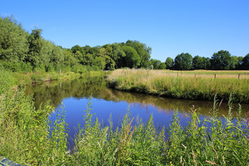Beautiful scenic idyllic typical lower rhine (Niederrhein) green rural landscape, river Niers, forest, blue summer sky - Wachtendonk, Germany
