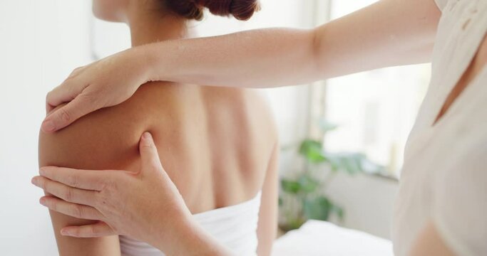 Back and shoulder of woman being massaged by hands and thumb of a masseuse. Rearview of female customer getting an assessment from a physio in a day spa. Massaging to get rid of stress and tension