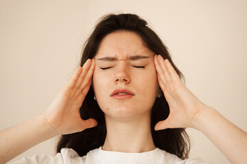 Depressed girl with migraine headache. Sad woman touches temples because of stress and despair in...