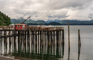 Reflection of the wooden pier in the cold ocean at Icy Strait Point in Alaska on cloudy day