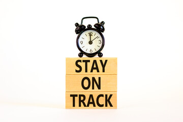 Stay on track symbol. Concept words Stay on track on wooden blocks on a beautiful white table white background. Black alarm clock. Business, motivational and stay on track concept. Copy space.