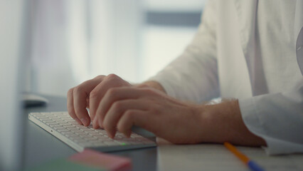 Closeup doctor hands typing on computer keyboard. Physician working remotely.