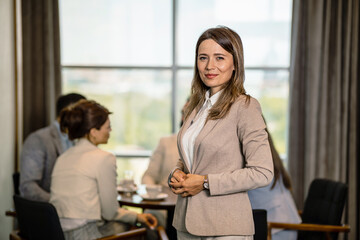 portrait of a young female team leader smiling with her co-workers in the background