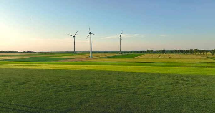 Aerial drone view of wind power turbines, part of a wind farm. Wind turbines on green field in countryside. Wind power plant..