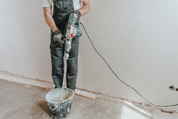Builder in work overalls plastering a wall indoor