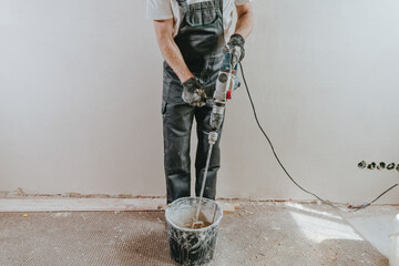 Builder in work overalls plastering a wall indoor