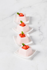 Mini Strawberry cream dessert, Panna Cotta in the form of square portions. Light background