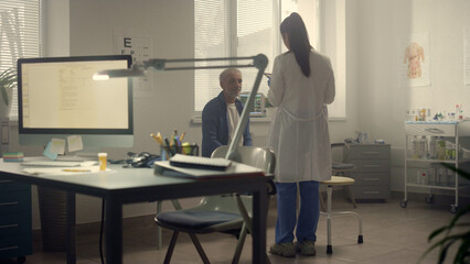 Doctor consulting old man in clinic. Woman physician talking with senior patient