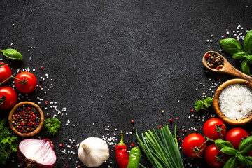 Food background on black stone table. Fresh vegetables, herbs and spices. Ingredients for cooking with copy space.