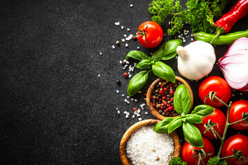 Fresh herbs and vegetables on black. Ingredients for cooking with copy space.