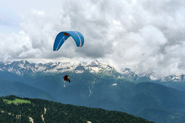 Beautiful view of snow-capped mountains with paragliders flying in tandem. Extreme sport.