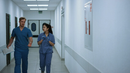 Doctors walking down corridor discussing diagnose. Medics hurrying to operation.