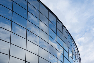 Fototapeta na wymiar Mirrored windows of a modern building reflect the blue sky and clouds