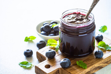 Blueberry jam in the glass jar with fresh berries. Homemade dessert,