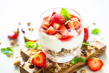 Parfait with cream or yogurt, jam and fresh berries in the glass jar. Healthy summer dessert.
