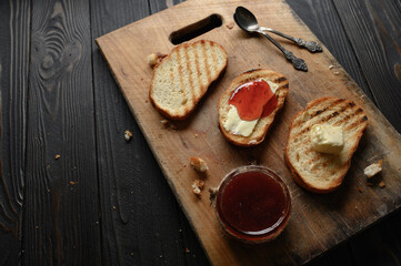 Toast bread with homemade strawberry jam and on rustic table with butter for breakfast or brunch.