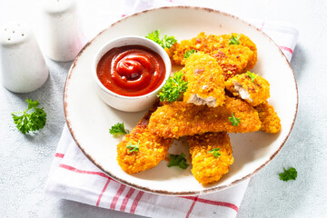 Chicken nuggets with ketchup sauce at white table.
