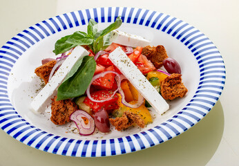 Greek salad with feta cheese and aromatic herbs. On a white background, isolated. Vegetarian dish.
