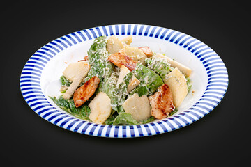 Caesar salad with chicken, Romano salad, with a sauce of blue cheese. On a dark background, isolated.