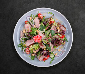 Josper-oven veal salad with sauce. On a dark background, isolated.