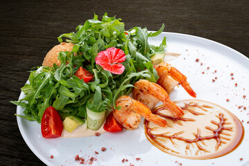 Salad with shrimp, arugula and crispy egg with oyster sauce. On a dark background, isolated.