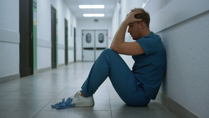 Man surgeon sitting floor clinic hallway closeup. Doctor after hard pandemic day