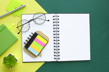 Still life, business, stationery or education concept: top view of open notebook with blank pages and glasses on green and yellow background, ready to add or mockup