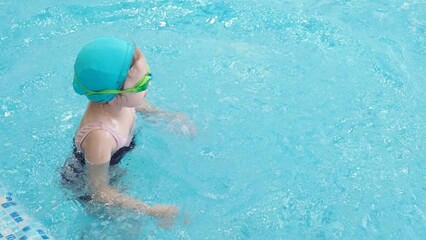 Little girl learning to swim with mother in big sport pool. Swimming school for small children. Healthy kid enjoying active lifestyle. Preschooler practicing with foam pad and noodle.