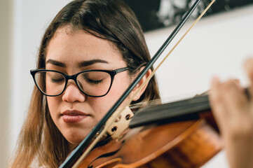 Caucasian young woman with closed eyes playing and feeling the music of the violin.