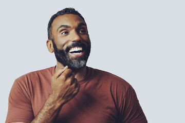 headshot portrait of a handsome bearded mid adult man smiling looking away at copy space against gray background studio shot