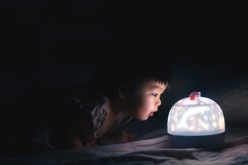 Asian baby girl close stare LED lamp with interest, low light situations.