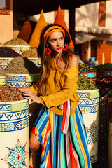 A beautiful girl stands near spices in the market of the city of Essaouira in Morocco