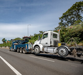 Fototapeta na wymiar Dark blue powerful mobile big rig towing semi truck tow broken semi truck running on the wide highway road