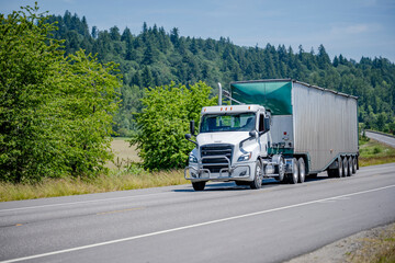 Obraz premium Day cab local delivery white big rig semi truck transporting cargo in bulk corrugated semi trailer driving on the winding road in Columbia Gorge