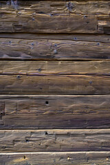 Wooden exterior of a rustic cabin built out of hand-hewn timber, as a textured background
